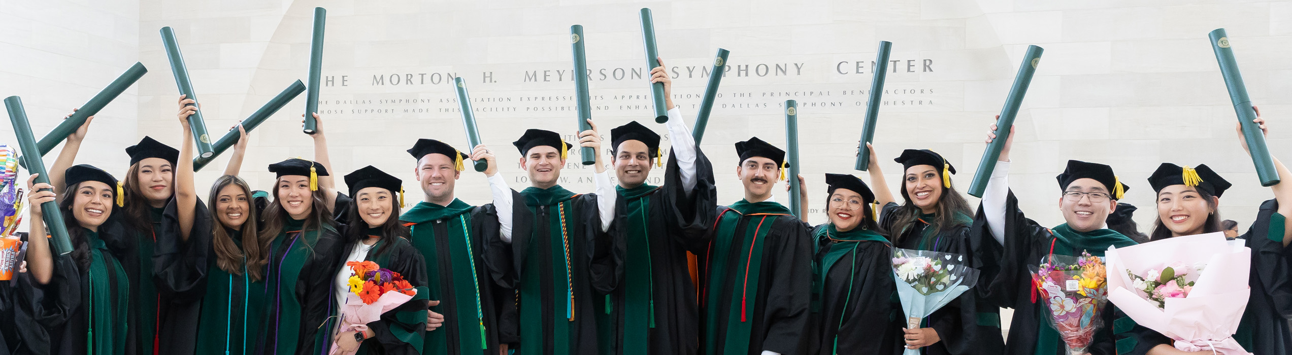 new alumni holding up their diplomas