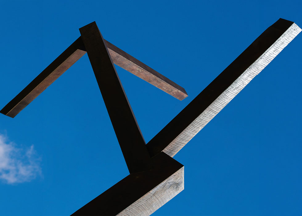 a beam sculpture in front of a clear blue sky 