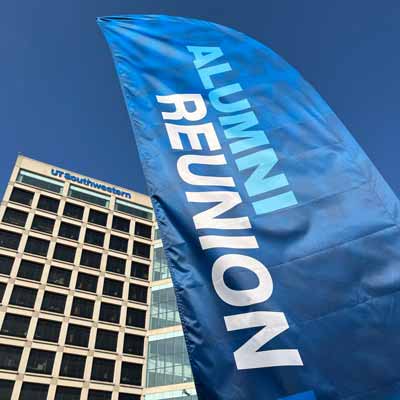 A blue banner with the words Alumni Reunion stands in front of a high-rise campus building with the UT Southwestern logo across the top of the roof.