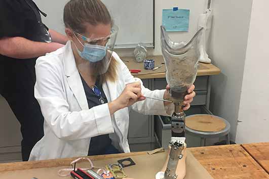 Caitlin Peters adjusts a prosthetic leg on a workbench