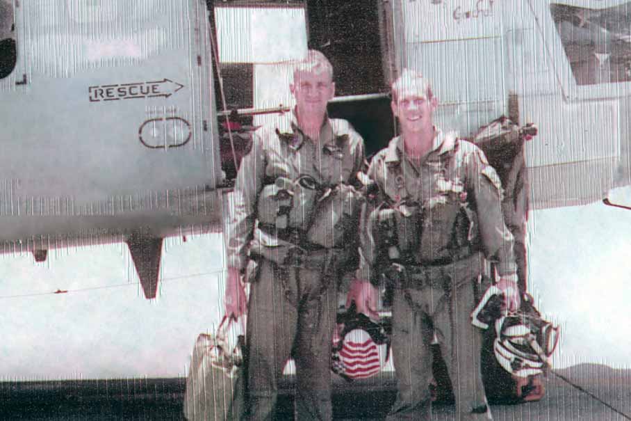 Wearing their flight suits, James Thornton and a fellow serviceman pose in front of a helicopter in Kaneohe Bay, Hawaii