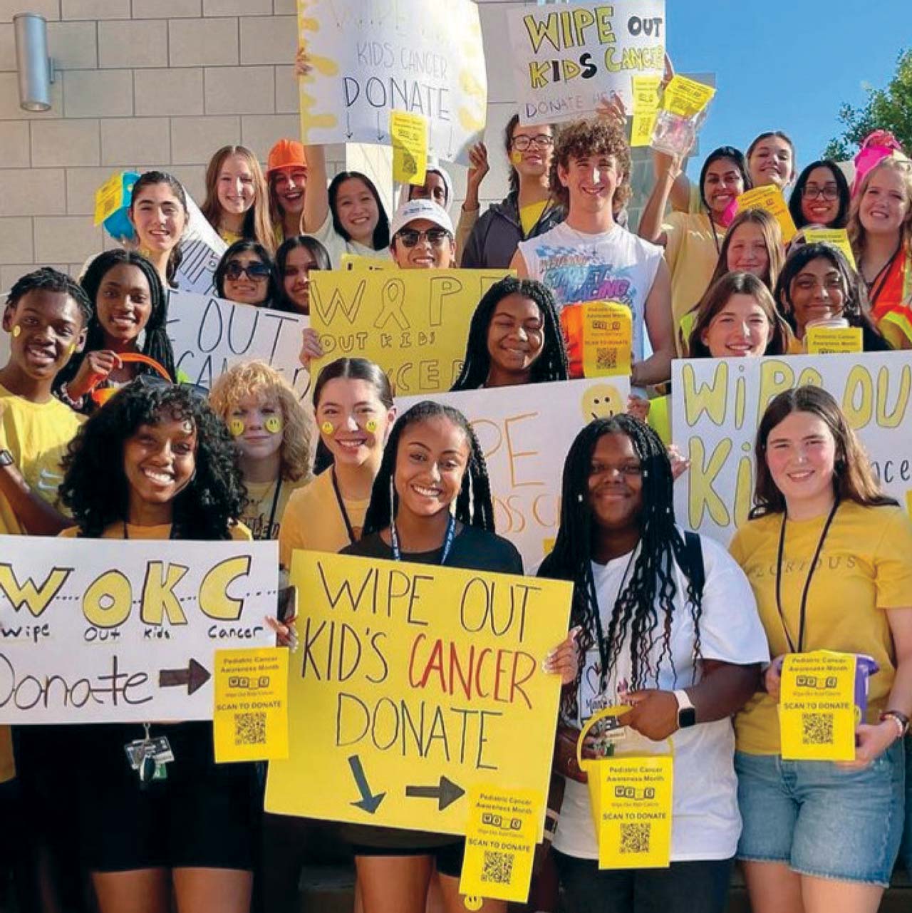 Group photo of high school students wearing yellow and holding signs supporting Wipe Out Kids' Cancer's fundraising challente.