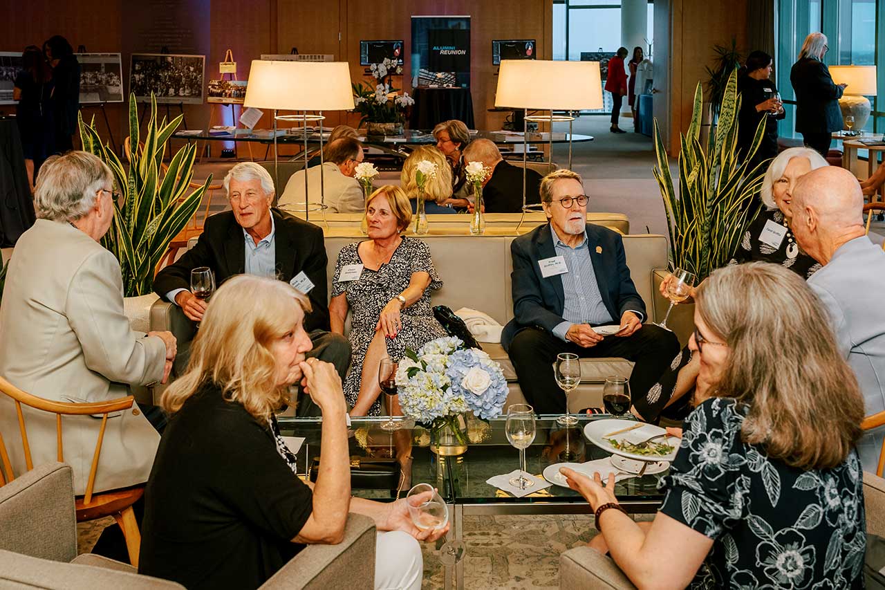 People seated on lounge furniture spread throughout the room talk in small groups