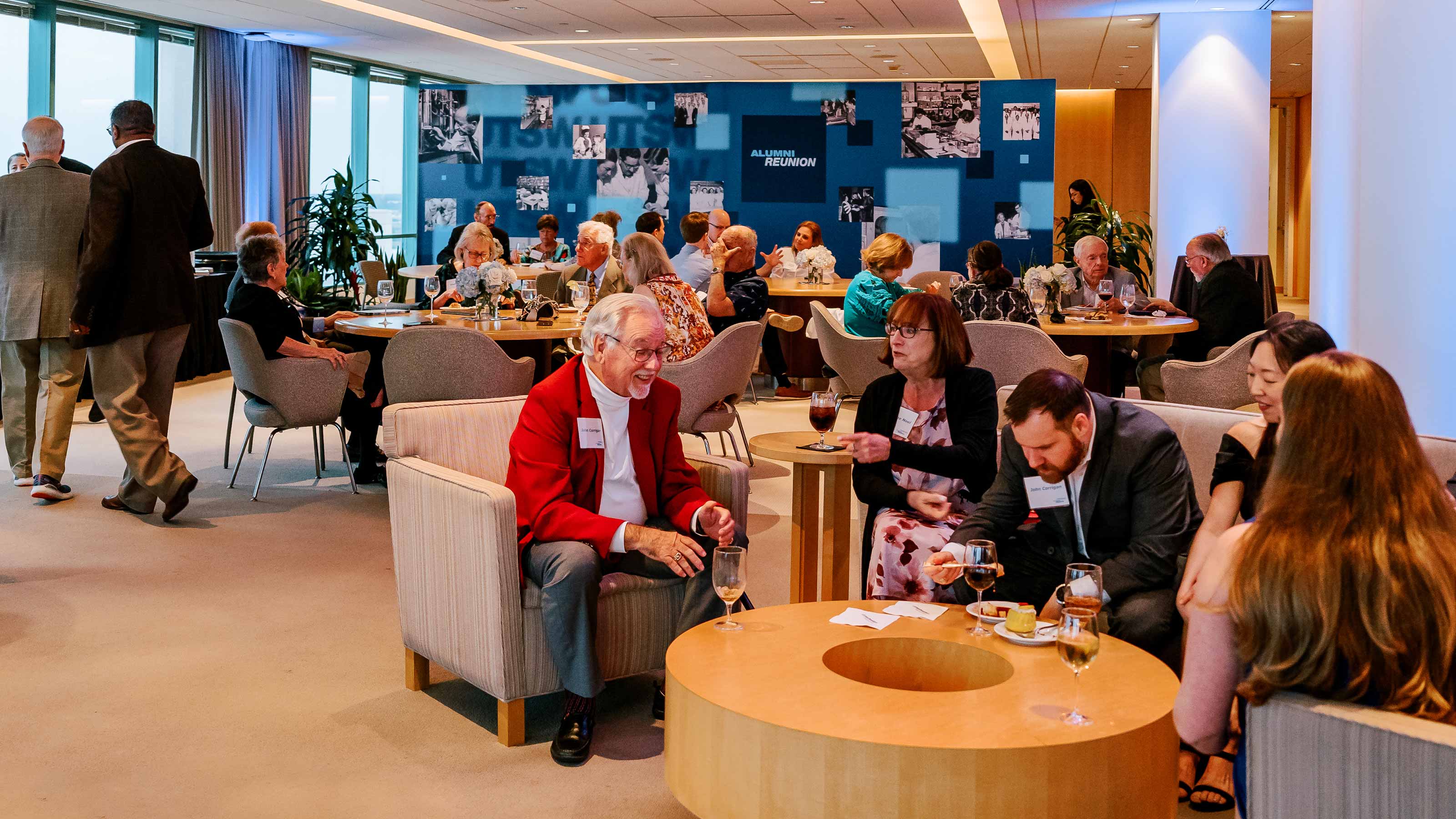 Small groups of people talk among themselves while standing and seated at tables