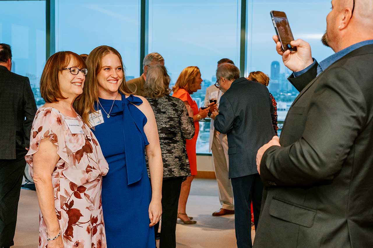 A man holding a cell phone takes a photo of two women