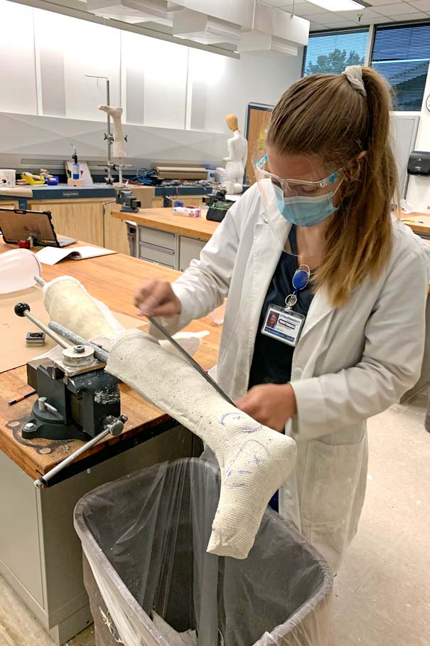 Caitlin Peters removes material from a plaster leg cast with a file