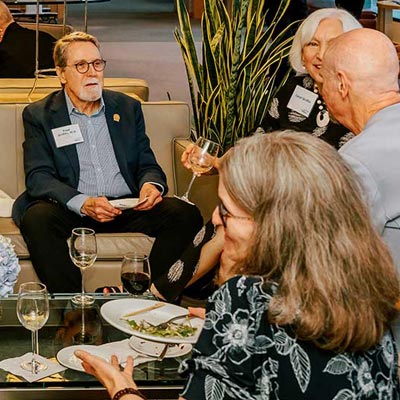 People seated on lounge furniture spread throughout the room talk in small groups